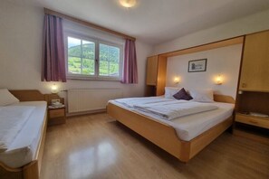 A hotel room with a large bed, a smaller bed, a window with curtains, a radiator, and a wooden wardrobe. - Apartment Mary (4-8 people) (Fürth)