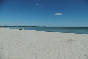 Ein Strand mit weißem Sand und ruhigem Wasser.