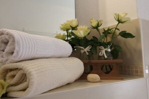 Ein Badezimmer mit einem Stapel Handtüchern, einer Vase mit Blumen und einem dekorativen Holzobjekt.
