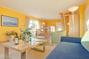 Ein Wohnzimmer mit einer Couch, einem Glastisch und einem Essbereich mit Stühlen und einem Tisch.