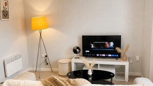 En stue med sofa, fjernsyn, lampe og radiator.