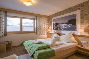 A bedroom with a bed, a window with curtains, a painting on the wall, and a bedside table. - Holiday apartment with 2 bedrooms (Hippach)