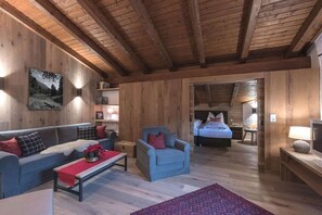 Ein Holzinterieur mit einer Couch, einem Sessel und einem Bett im Hintergrund.