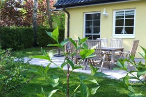 Ein gelbes Haus mit Terrasse, Tisch und Stühlen.