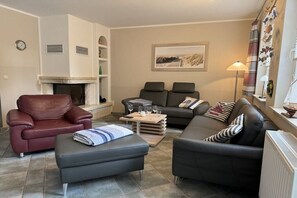 Ein Wohnzimmer mit Kamin, Ledersofas, einem Couchtisch und einer Wanduhr.