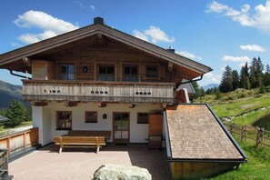 Eine Holzhütte mit Balkon, Bank und kleinem Außenbereich.