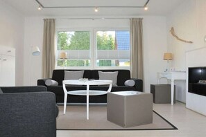 Ein modernes Wohnzimmer mit einer Couch, einem Couchtisch, einem Fernseher und einem Schreibtisch.
