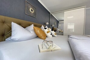 Ein Hotelzimmer mit einem großen Bett, einem Kopfteil, einem Spiegel und einem gerahmten Bild an der Wand.