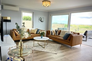 Ein modernes Wohnzimmer mit einer Couch, einem Couchtisch und Blick ins Freie.