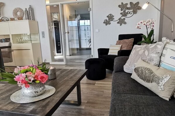 Ein modernes Wohnzimmer mit einer Couch, einem Couchtisch mit Blumenarrangement und einer Wanddekoration.