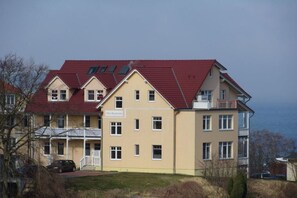 Ein mehrgeschossiges Gebäude mit rotem Dach, Balkonen und einem Schild mit der Aufschrift 'Villa Behrendtzen'.