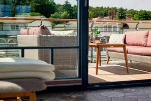 A balcony with wicker furniture, a sofa, and a table with cushions. - Villa in Sellin with swimming pool (Sellin)