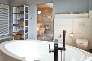 Ein modernes Badezimmer mit einer freistehenden Badewanne, einer eingebauten Ablage und einer sichtbaren Toilette.