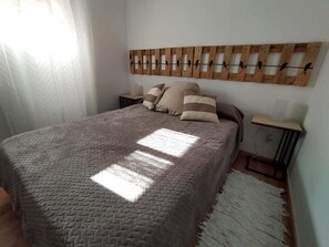 Un dormitori amb un llit, una decoració de paret de fusta, una taula de nit i una catifes.