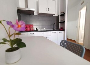 Una cuina moderna amb armaris blancs, una campana extractora d'acer inoxidable i un taulell negre.