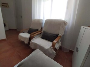 Habitació amb dues cadires, una taula petita i un armari.