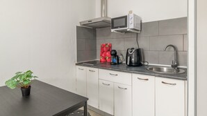 Een kleine keuken met een magnetron, waterkoker en een potplant.