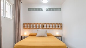 Een slaapkamer met een bed, een houten hoofdbord, een nachtkastje en een raam met gordijnen.
