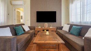 Ein Wohnzimmer mit zwei Sofas, einem Couchtisch, einem Flachbildfernseher und einer gestreiften Wand.