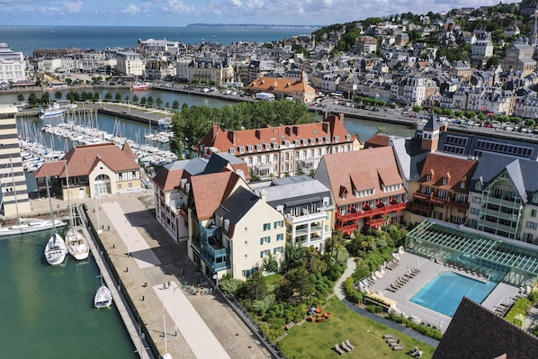 A coastal cityscape with a marina, historic buildings, and a swimming pool area. - Deauville Harbour View Apartment for 4 (Deauville)