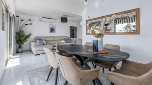 Uma sala de estar moderna com uma mesa de jantar, sofás e um espelho grande.