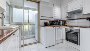 Uma cozinha moderna com armários brancos, forno embutido e micro-ondas.
