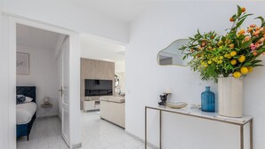 Uma sala de estar moderna com sofá, TV, mesa de console com objetos decorativos e um espelho na parede.