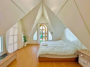 A triangular attic bedroom with a bed, a window, and a door. - BanKraJome Magodkan Beach (เขาแดง)