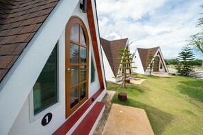 A modern, triangular-roofed building with a large window and a door, surrounded by a well-maintained lawn and a clear sky. - BanKraJome Magodkan Beach (เขาแดง)