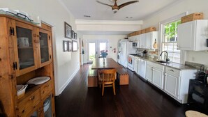 A kitchen with wooden cabinets, a dining table, and a ceiling fan. - Historic Creole Cottage In The Marigny (New Orleans)