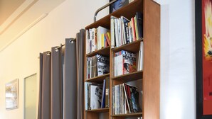Una habitación con sofá de cuero, una mesa de centro de madera, una estantería y una puerta con cortinas.