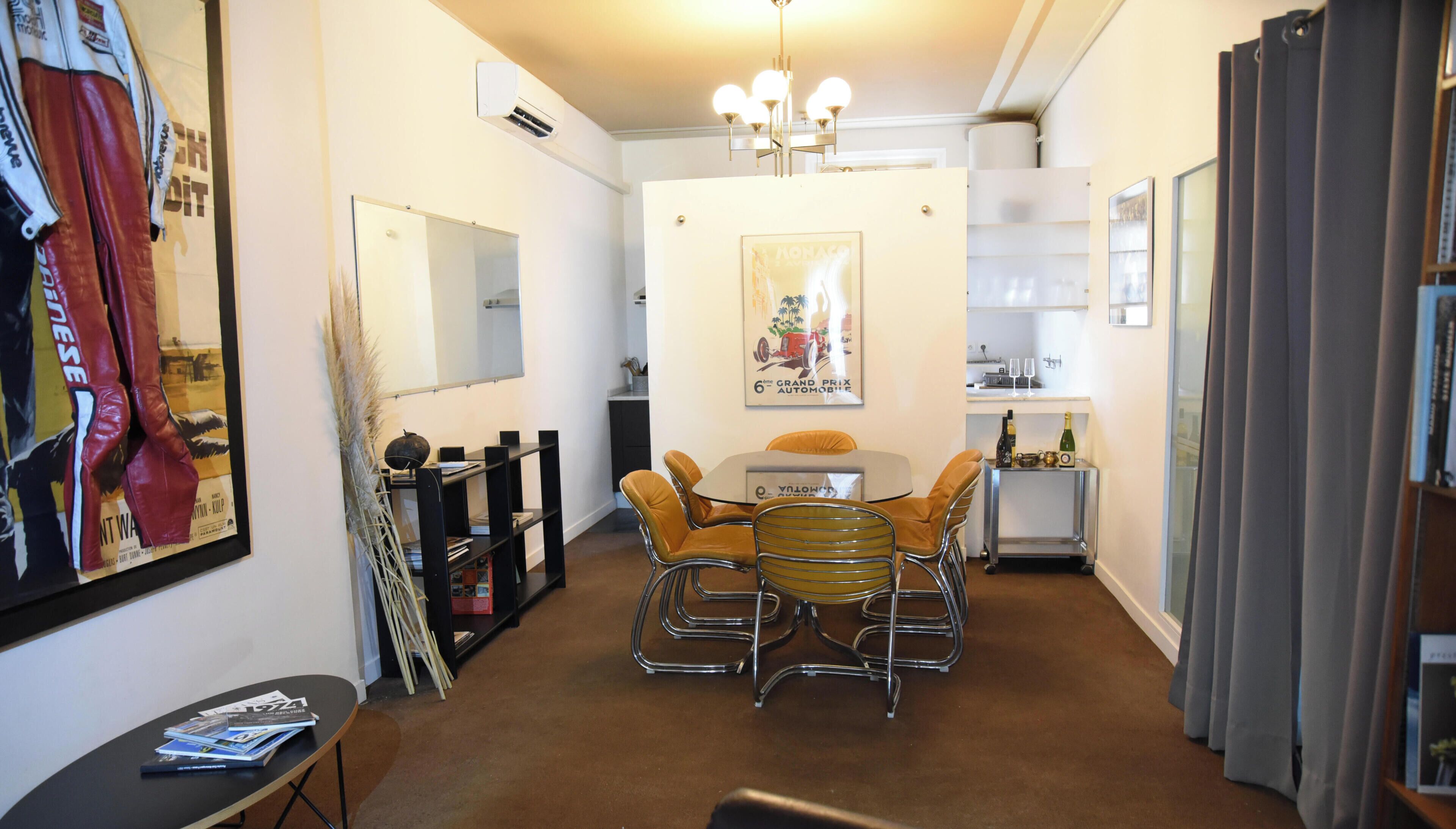 A compact living space with a dining area, a small kitchen, and a mirrored wall.