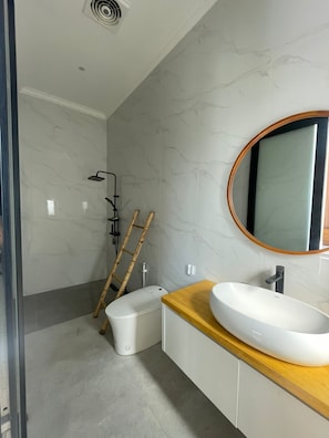 Een moderne badkamer met een wit wastafel, een houten wastafelmeubel, een grote spiegel en een douche met een treeplank.
