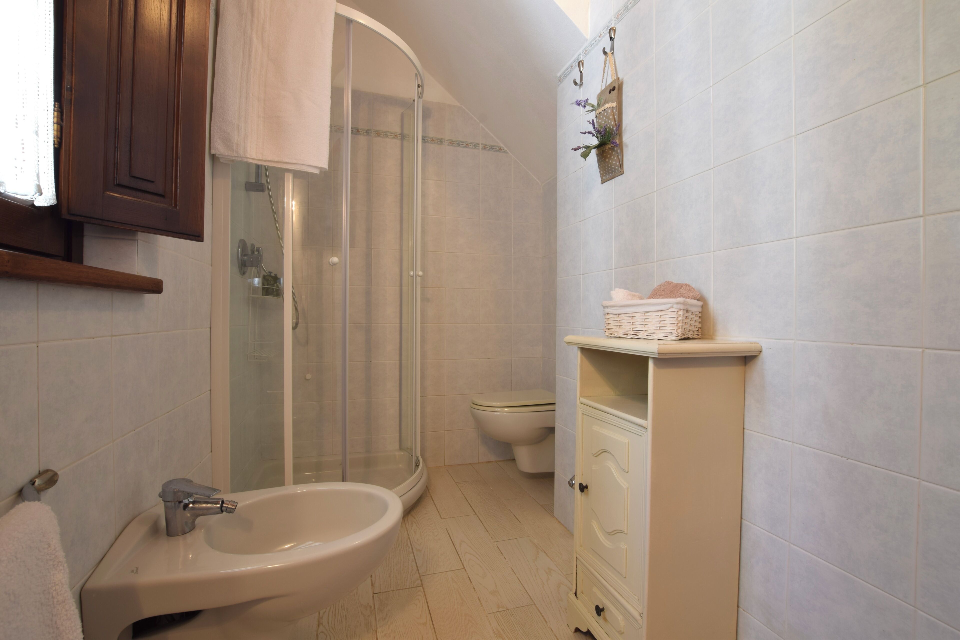 Une salle de bain équipée d’une douche, de toilettes, d’un lavabo et d’un meuble de rangement.