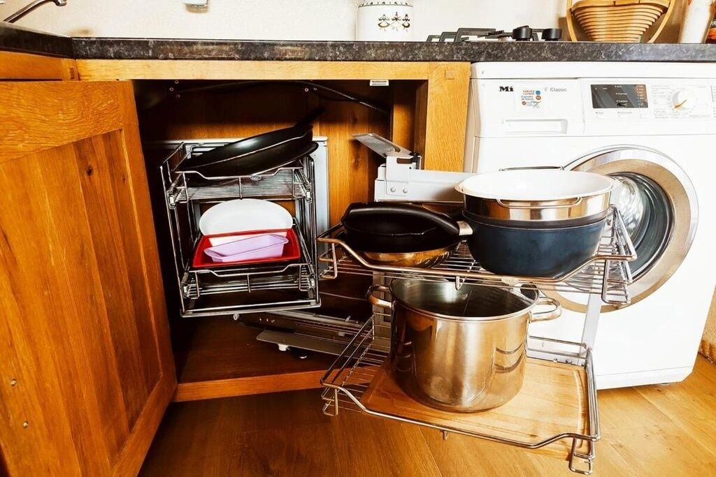 A kitchen with a dishwasher, a stove, and a pot rack.
