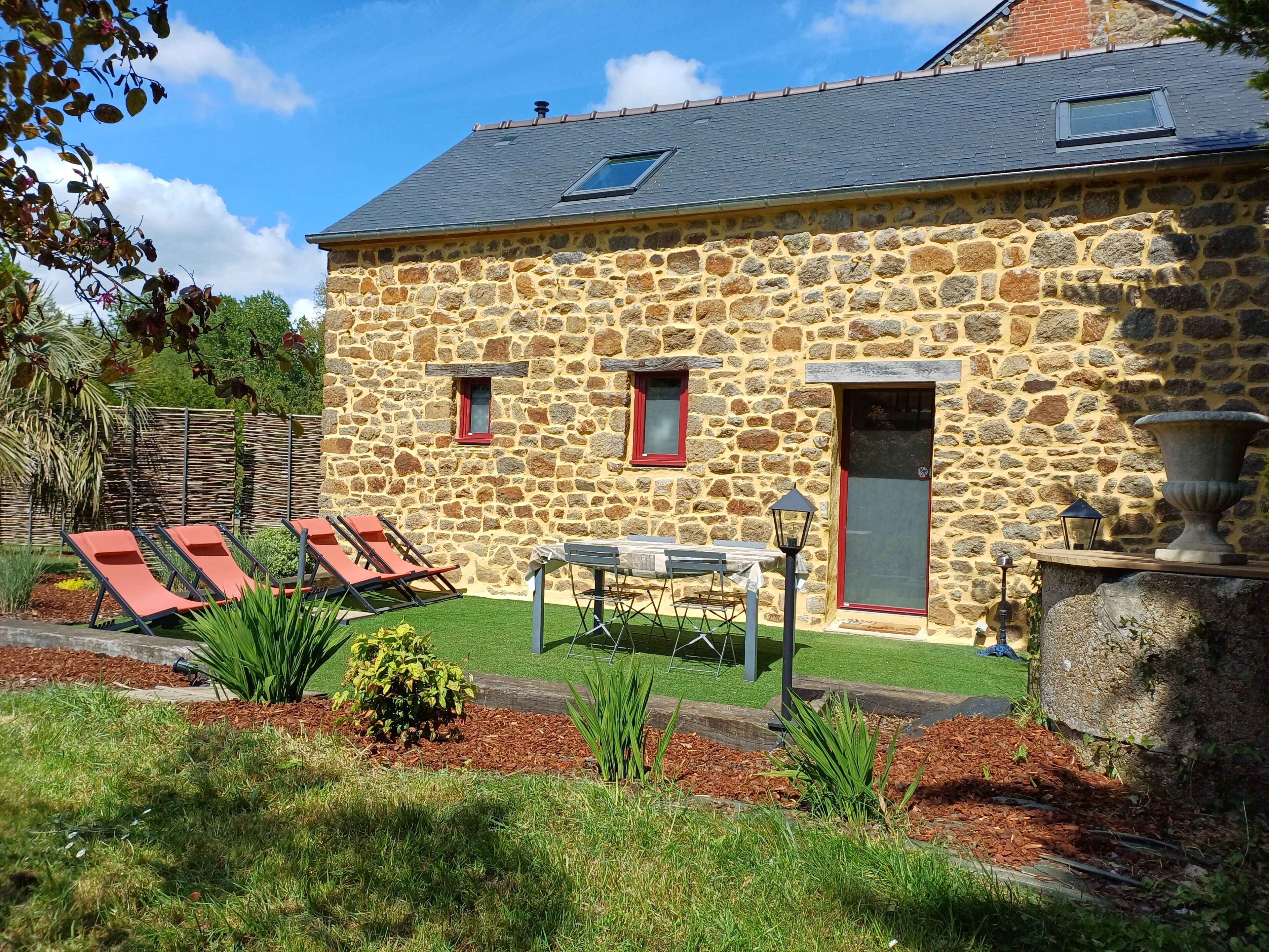 A stone building with a small patio, two windows, and a door.