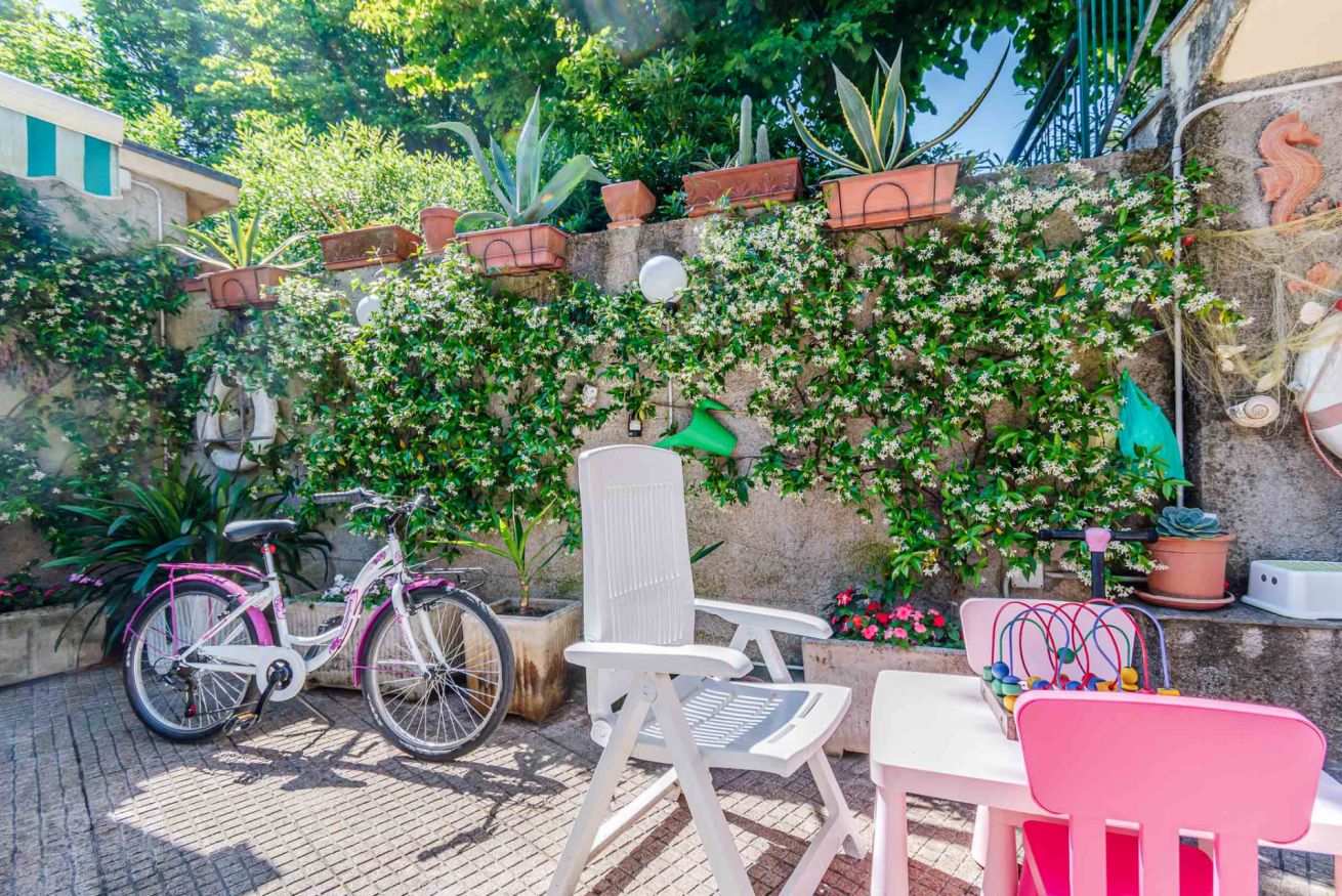 Een terras met een fiets, stoelen en plantenpotten.