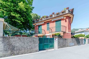 Um edifício de dois andares com fachada vermelha, persianas verdes e portão fechado.