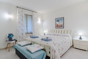 A bedroom with a bed, bedside tables, a chair, a window with curtains, and a wall-mounted picture. - Cozy and charming 50 square meters ground-floor house with a private entrance, perfect for four people.The property is ideally located for those who want to fully enjoy the Moneglia seaside: the beach is just a 5-minute walk away. The train station is al (Moneglia)