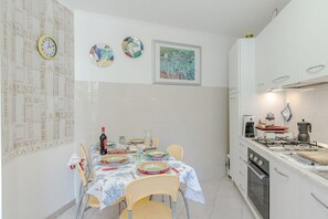 Eine Küche mit Esstisch für zwei Personen, einem Gasherd und einer Kaffeemaschine.