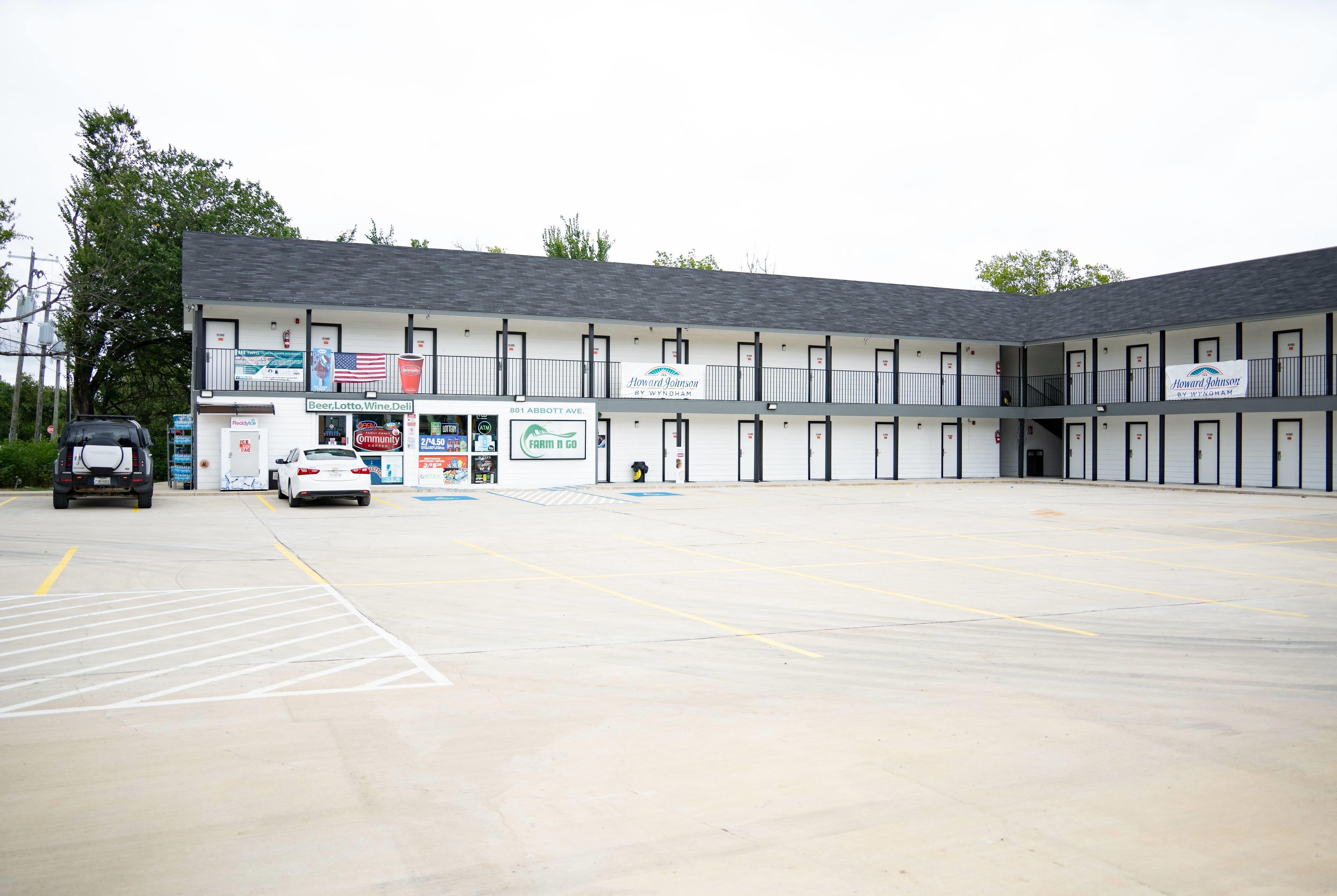 A motel with a parking lot and a storefront with various signs.