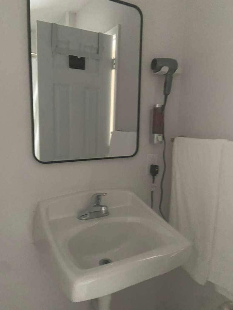 A bathroom with a white sink, a mirror, and a towel hanging on the wall.