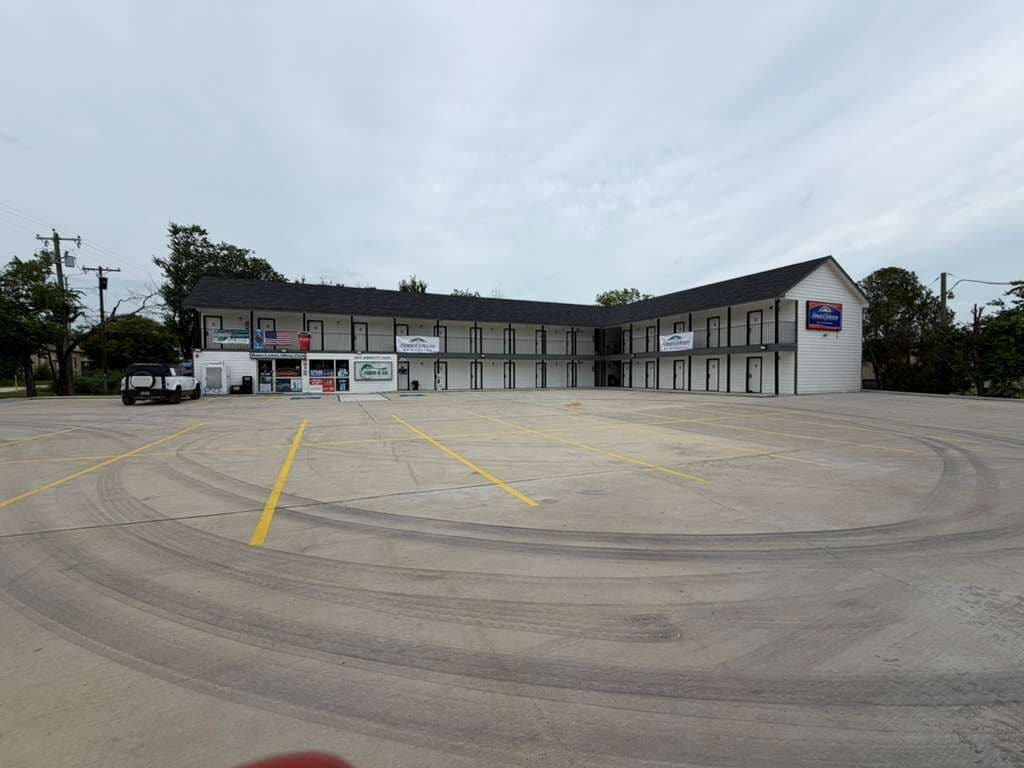 A large, multi-story motel with a central courtyard and a parking lot.