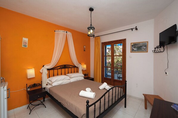 A hotel room with a bed, a bedside table, a desk, a chair, a TV, and a window with curtains.