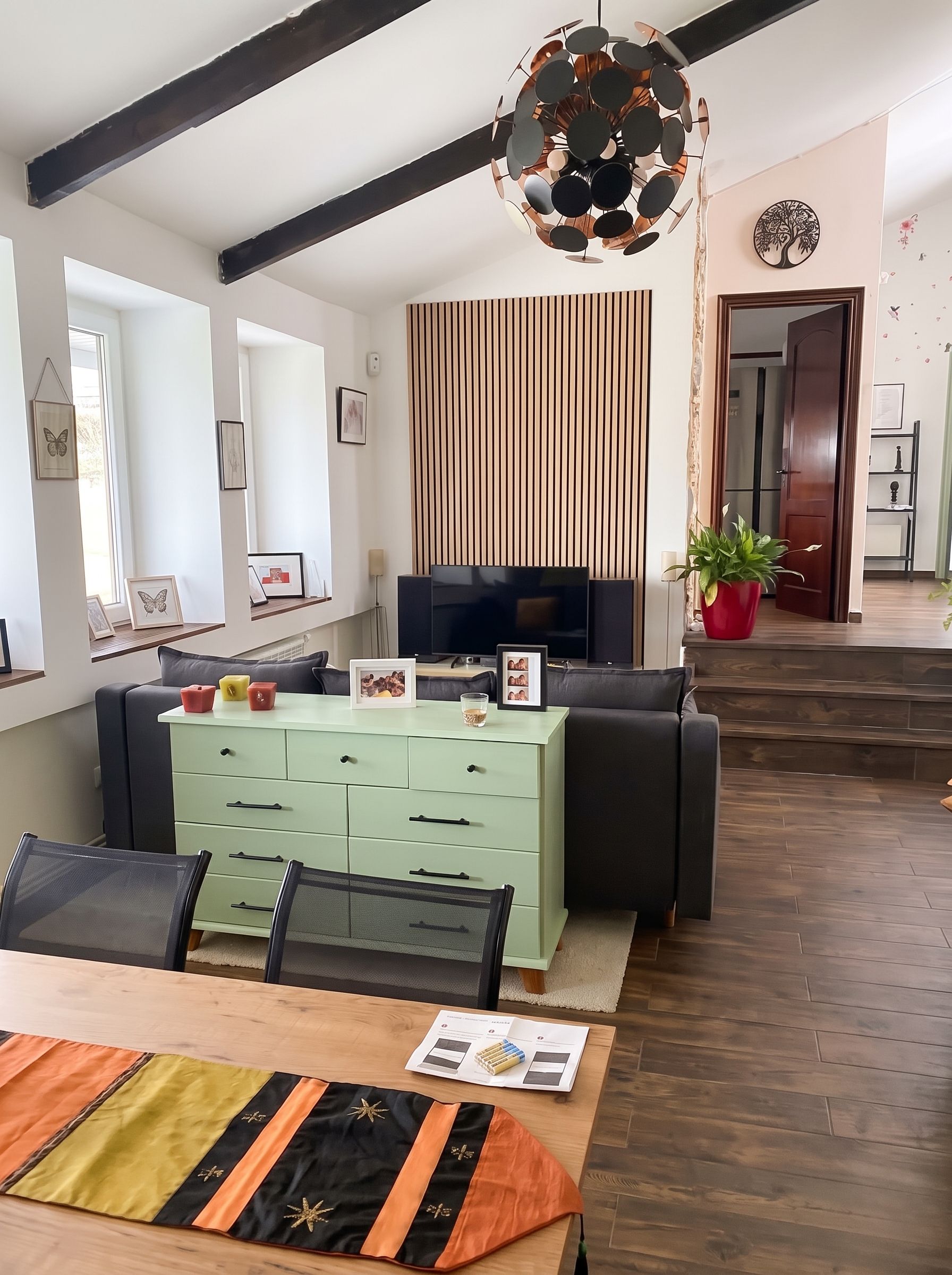 Ein modernes Wohnzimmer mit einer Couch, einem Fernseher und einem Essbereich mit Tisch und Stühlen.