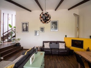 Ein Wohnzimmer mit einer Couch, einem Couchtisch, einem Fernseher und einer Treppe.