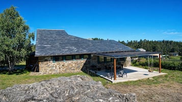 A stone building with a sloped roof and a covered patio area.
