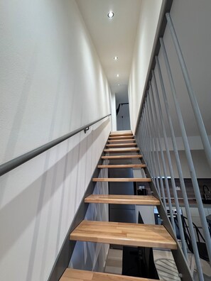 Eine moderne Treppe mit Holzboden und Metallgeländern, die zu einer oberen Etage führt.