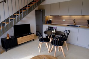 Eine moderne Küche mit Essbereich, einem eingebauten Fernseher und einer Treppe.