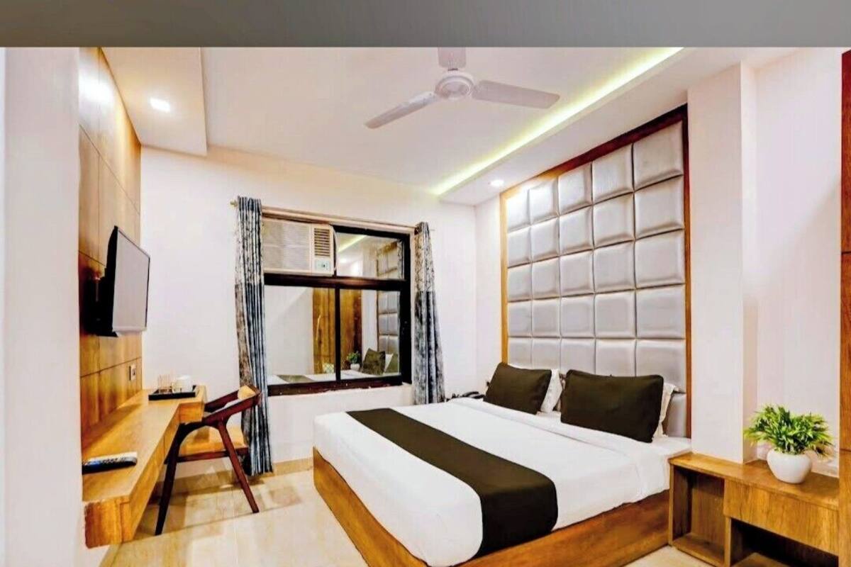 Une chambre d’hôtel moderne équipée d’un lit, d’un bureau, d’une télévision, d’un ventilateur de plafond et d’une fenêtre avec des rideaux.